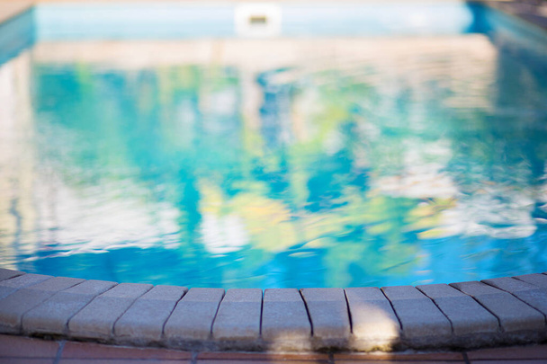 Widok na stronę basenu z niebieską wodą. Basen do wypoczynku w hotelu lub na terenie domu - Zdjęcie, obraz
