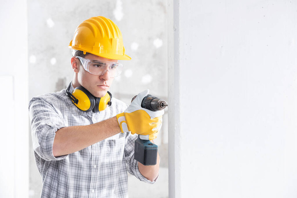 Builder drilling a hole in a new wall - Zdjęcie, obraz
