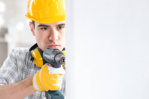 Young male construction worker drilling the wall - Photo, Image