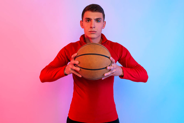 Nuori urheilullinen mies, jossa koripallo, poseeraa taustalla n
 - Valokuva, kuva