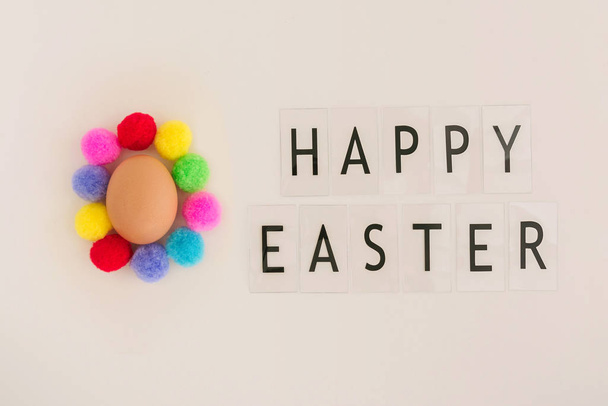 Velikonoční vajíčko s pestrobarevnými oříšky na béžovém pozadí a slovy Veselé Velikonoce. - Fotografie, Obrázek
