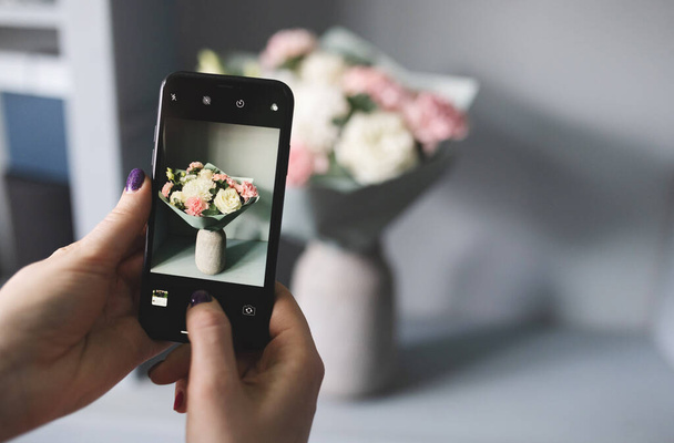 blogger takes a photo of a bouquet of flowers - Foto, Imagen