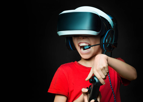 Girl in VR playing video games with excited face over dark background - 写真・画像