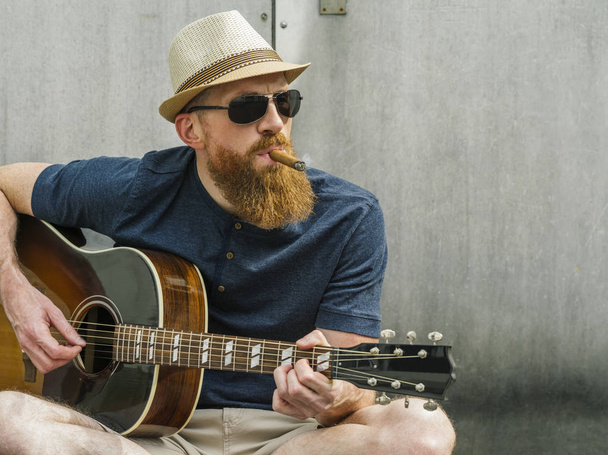 Man with fedora and cigar playing acoustic guitar - 写真・画像