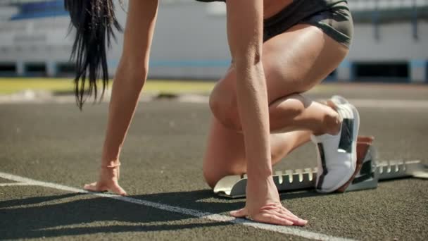 スローモーション:女性アスリートは400メートルでレースの開始を待ちます。女子アスリートは100メートル先でレースが始まるのを待ちますトレッドミルのパッドからスタジアムを走る. - 映像、動画