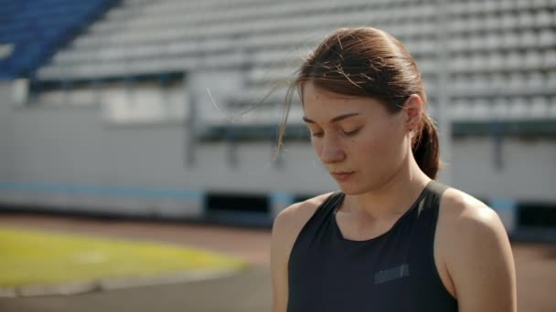 Slow motion portret van een mooie vrouw die loopt op het stadion tribunes met geconcentreerde diepe ademhaling en motiveren mezelf en bewustzijn voor de race. Onnodige emoties weggooien - Video