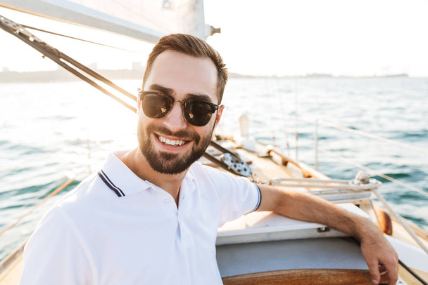 Handsome young amazing man outdoors on yacht in sea. - 写真・画像