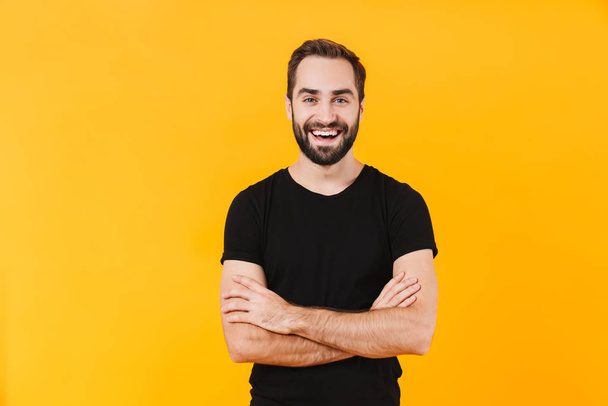 Image of happy man wearing basic black t-shirt smiling at camera - Foto, Imagen