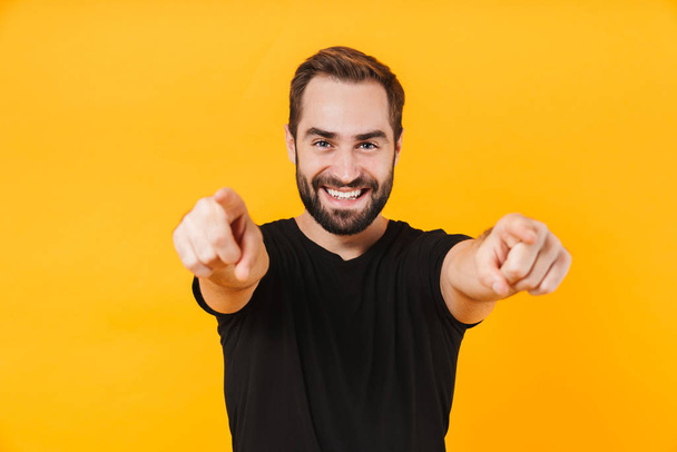 Image of cheerful man wearing t-shirt smiling and pointing finge - Fotó, kép