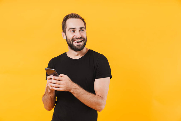 Image of successful man wearing t-shirt smiling and holding smar - Φωτογραφία, εικόνα