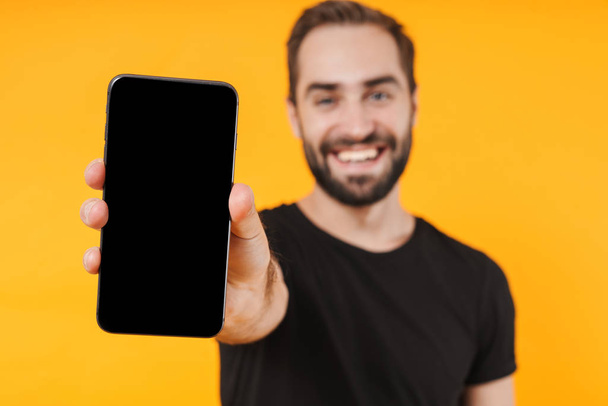Image of positive man smiling and showing cellphone at camera - 写真・画像
