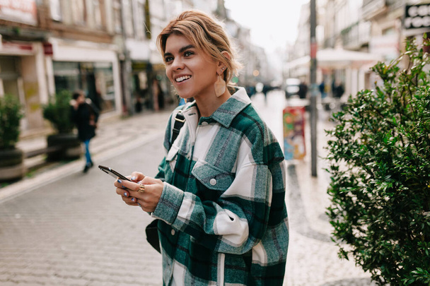 Attractive stylish young woman wearing stripped shirt walking on the old europe city with smartphone and enjoy her trip - Foto, immagini