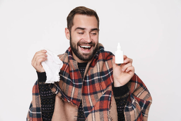 Portrait of ill guy wrapped in blanket sneezing and holding nose - Foto, Bild
