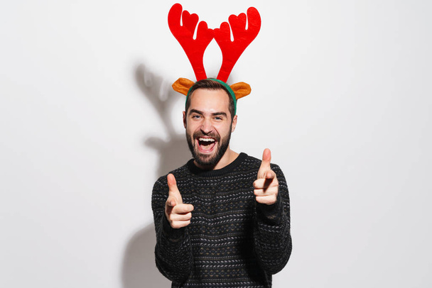 Image of man in Christmas reindeer antlers headband pointing fin - Photo, Image