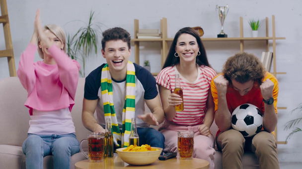 excited football fans clinking while celebrating at home  - Séquence, vidéo