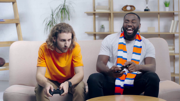 KYIV, UKRAINE - DECEMBER 9, 2019: happy african american man playing video game with friend  - Filmagem, Vídeo