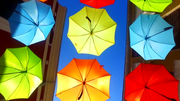 Opened, colorful, bold colored umbrellas, hanging from wires above the street. - Footage, Video