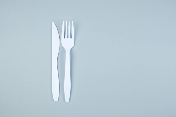 Gri arkaplandaki beyaz plastik çatal ve bıçak boşluğu kopyala  - Fotoğraf, Görsel