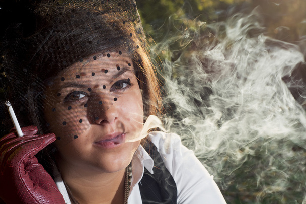 Joven hermosa morena fuma un cigarrillo en contraluz
 - Foto, Imagen