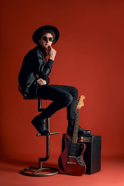 jeune musicien assis sur une chaise avec une guitare
  - Photo, image