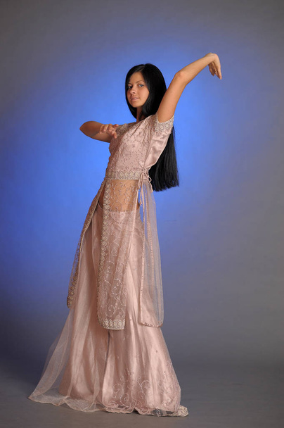 brunette girl in oriental dress on a blue background in the stud - Photo, Image