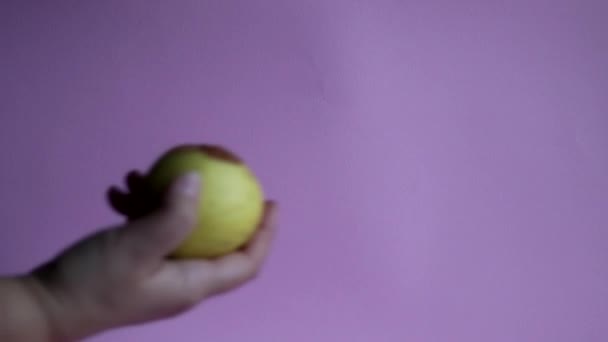 Ugly fruit rotten apple in a hand on a pink background. Poor storage conditions. - Кадры, видео