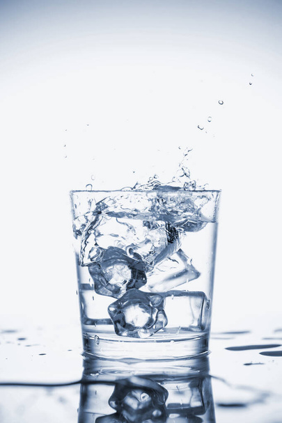 Чистая минеральная вода брызгает в стакан со льдом
. - Фото, изображение