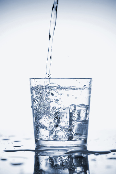 Чистая минеральная вода наливается в стакан со льдом
.  - Фото, изображение