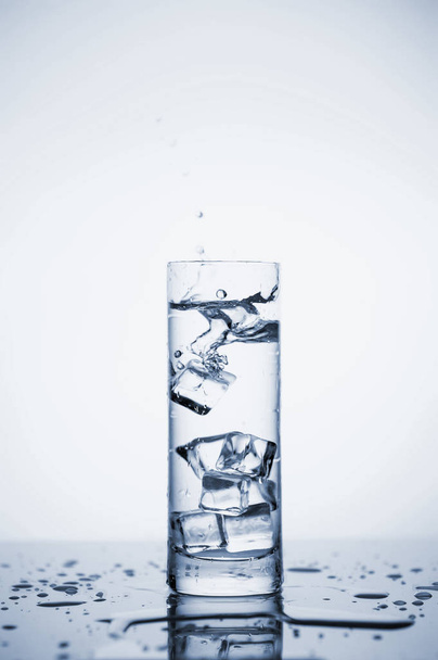 Прозорі бризки мінеральної води в склянці з льодом
. - Фото, зображення