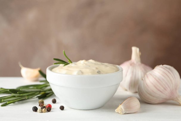 Bowl of garlic sauce, ingredients on white table against brown b - Photo, Image