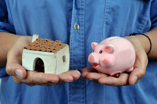 Hypotéka s domem a prasečí bankou v ruce - Fotografie, Obrázek