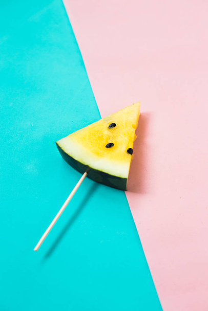 couper une tranche triangulaire de pastèque jaune mûre sur fond rose-bleu
 - Photo, image