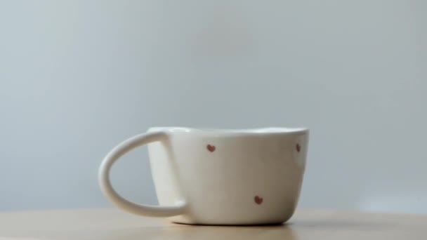 Close up of rotating cup of coffee on the wooden board with white background - Imágenes, Vídeo