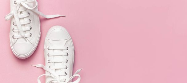 Zapatillas blancas de moda femenina sobre fondo rosa. Piso tendido, vista superior, espacio para copiar. Zapatos de mujer. Elegantes zapatillas blancas. Blog de moda o concepto de revista. Fondo de zapato minimalista, zapatos deportivos
 - Foto, imagen