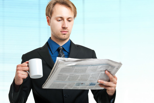 Businessman holding cup and reading a newspaper - Zdjęcie, obraz