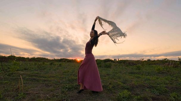 Gelukkige vrouwelijke dans in de zomervelden tijdens prachtige zonsondergang - Foto, afbeelding