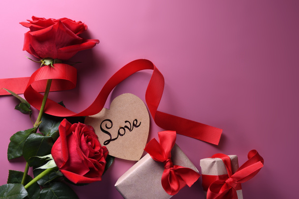 Sevgililer Günü arkaplanındaki tebrik kartı aşk sembolleri, pembe arka planda gözlüklü kırmızı kalp gülleri hediyeleri. Kopyalama alanı ve metin içeren üst görünüm. Düz konum - Fotoğraf, Görsel