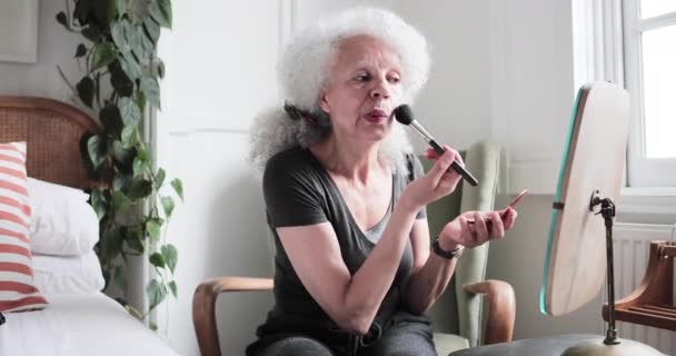 Mixed race senior adult woman putting makeup on - Materiał filmowy, wideo