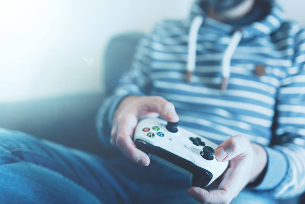 man on sofa using wireless controller to play video games - Photo, Image