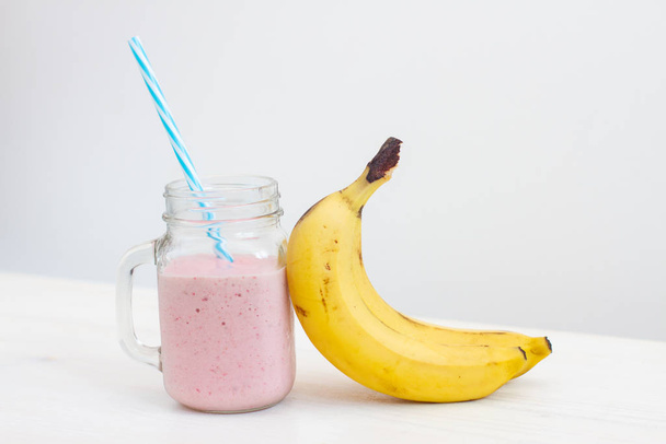 friss hideg rózsaszín smoothie kék szívószállal banánnal - Fotó, kép