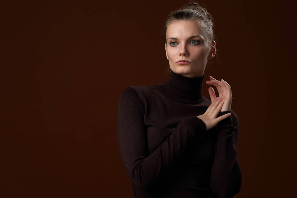 Beautiful girl in a maroon turtleneck on a brown background - Foto, afbeelding