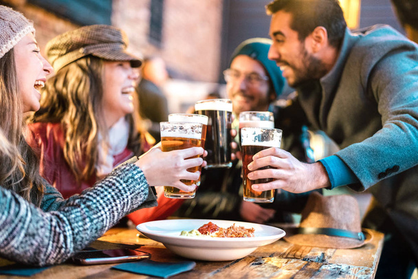 Vriendelijke jongens naderen gelukkige meisjes in brouwerij pub buiten in de winter - Vriendschap concept met jongeren die samen dronken plezier drinken bier op happy hour promotie - Levendige kleurenfilter - Foto, afbeelding