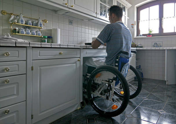 man on wheelchair cooking some food at the kitchen - Φωτογραφία, εικόνα