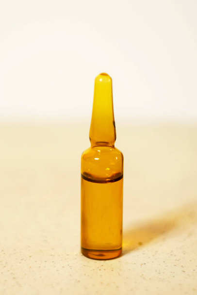 Brown ampoule with medicine on light background. Illness treatment. Pharmaceutical business. Skincare products - Φωτογραφία, εικόνα