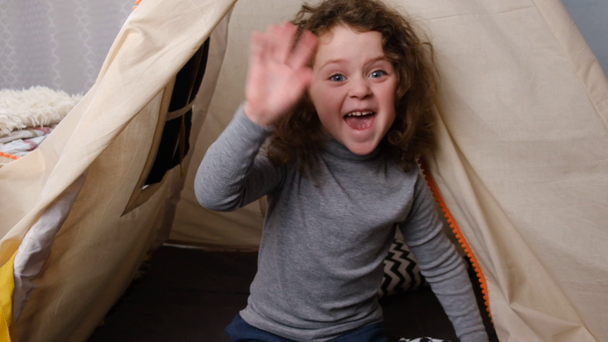 Cute little vlogger looking at webcam, smiling child girl talking to camera making video call vlog communicating online sitting in tent at children's room. Slow motion - Footage, Video