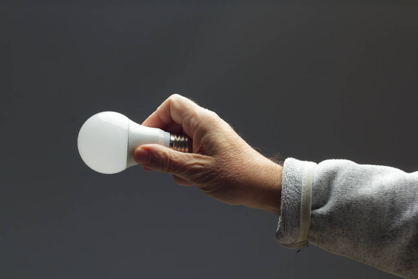 Energy saving light bulb in the hand of an adult - Foto, Imagen