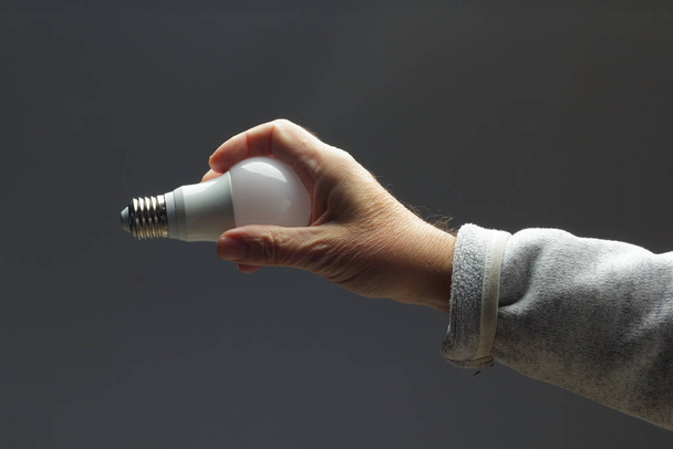 Energy saving light bulb in the hand of an adult - Photo, Image