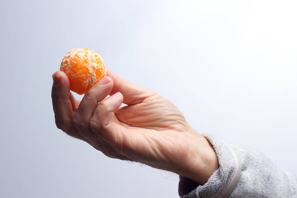 Tangerine slice in the hand of an adult person - Valokuva, kuva