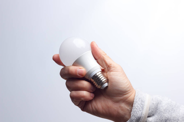 Lâmpada economizadora de energia na mão de um adulto
 - Foto, Imagem