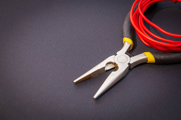 Pliers tool and red wires for electrician closeup, service and repairing concept - Fotó, kép